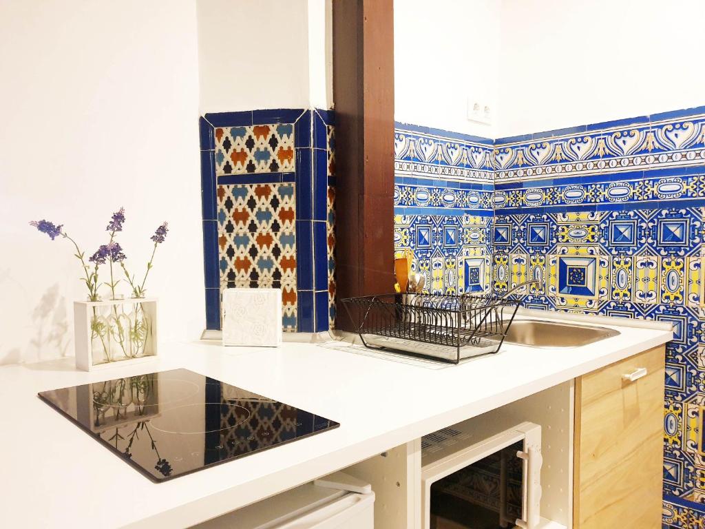 a kitchen with a sink and blue and white tiles at Palace-House Hércules 92 in Seville