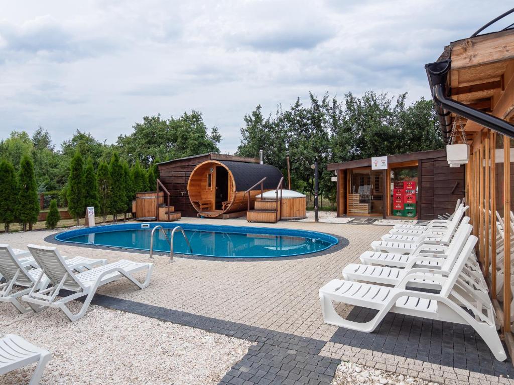 una piscina con tumbonas blancas junto a una cabaña en Ośrodek wypoczynkowy - Wczasy w Cichowie, en Cichowo