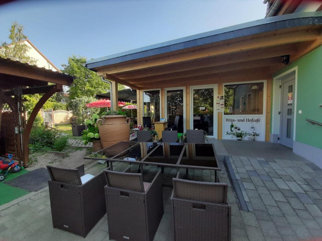 eine Terrasse mit Stühlen und Tischen vor einem Gebäude in der Unterkunft Pension Sommerfrische in Nebra