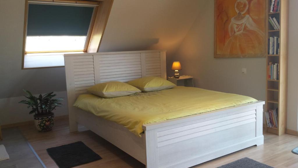 um quarto com uma cama branca com lençóis amarelos e uma janela em Notre Rêve - Chambre d'hôtes em Marmoutier