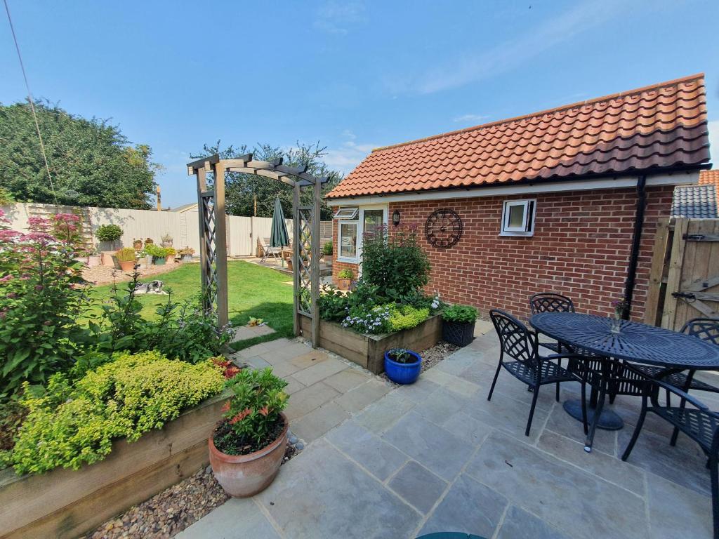 a patio with a table and chairs in a backyard at The Garden Room in Leiston