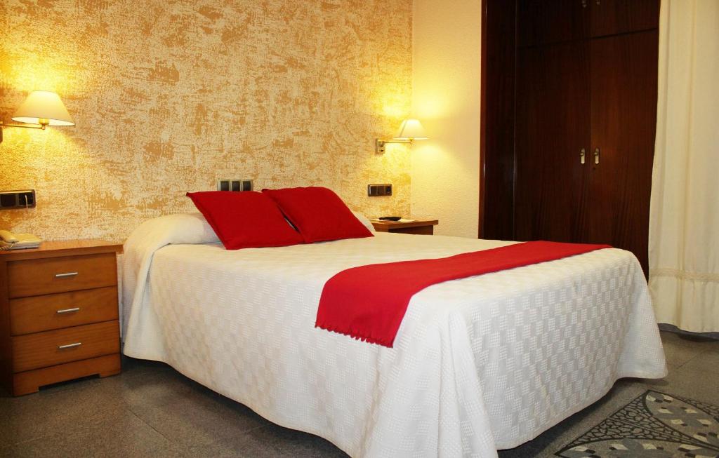 a bedroom with a large white bed with red pillows at Hotel La Paz in Úbeda