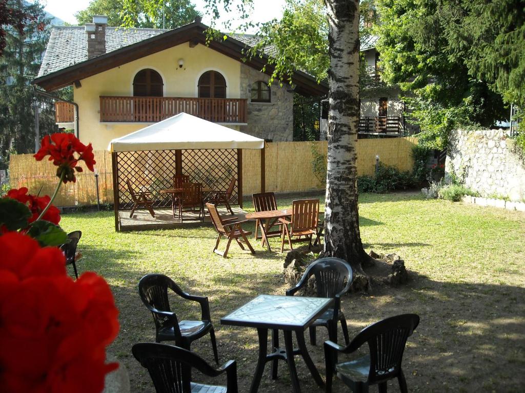 einen Tisch und Stühle in einem Garten mit einem Baum in der Unterkunft Hotel Tripoli La Margherita in Limone Piemonte