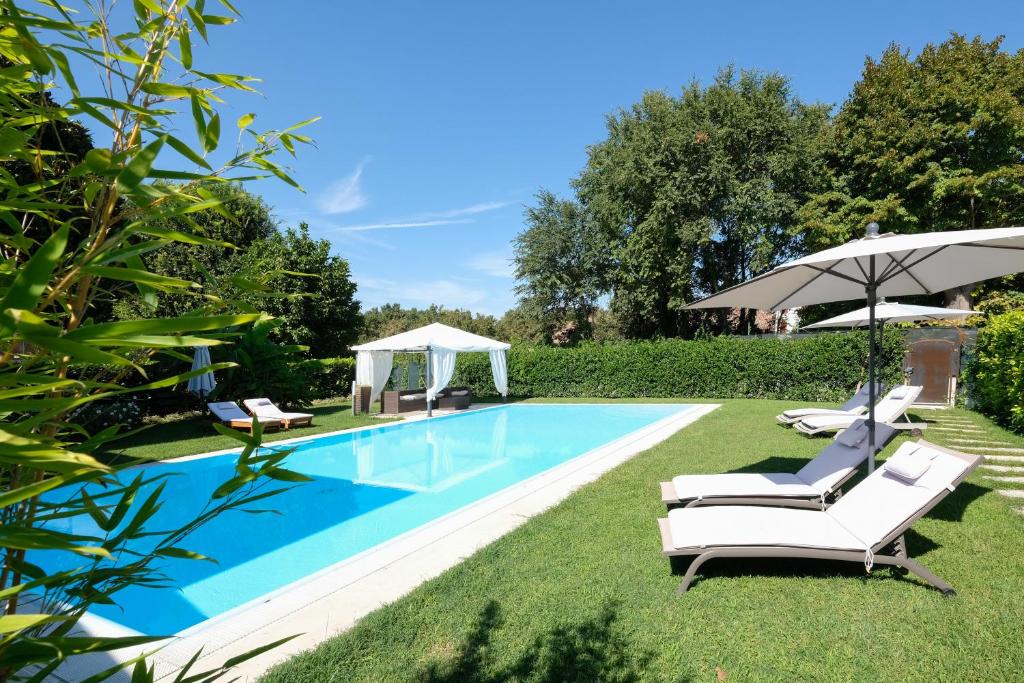 a swimming pool with lawn chairs and umbrellas at La Celeste Galeria in Mantova