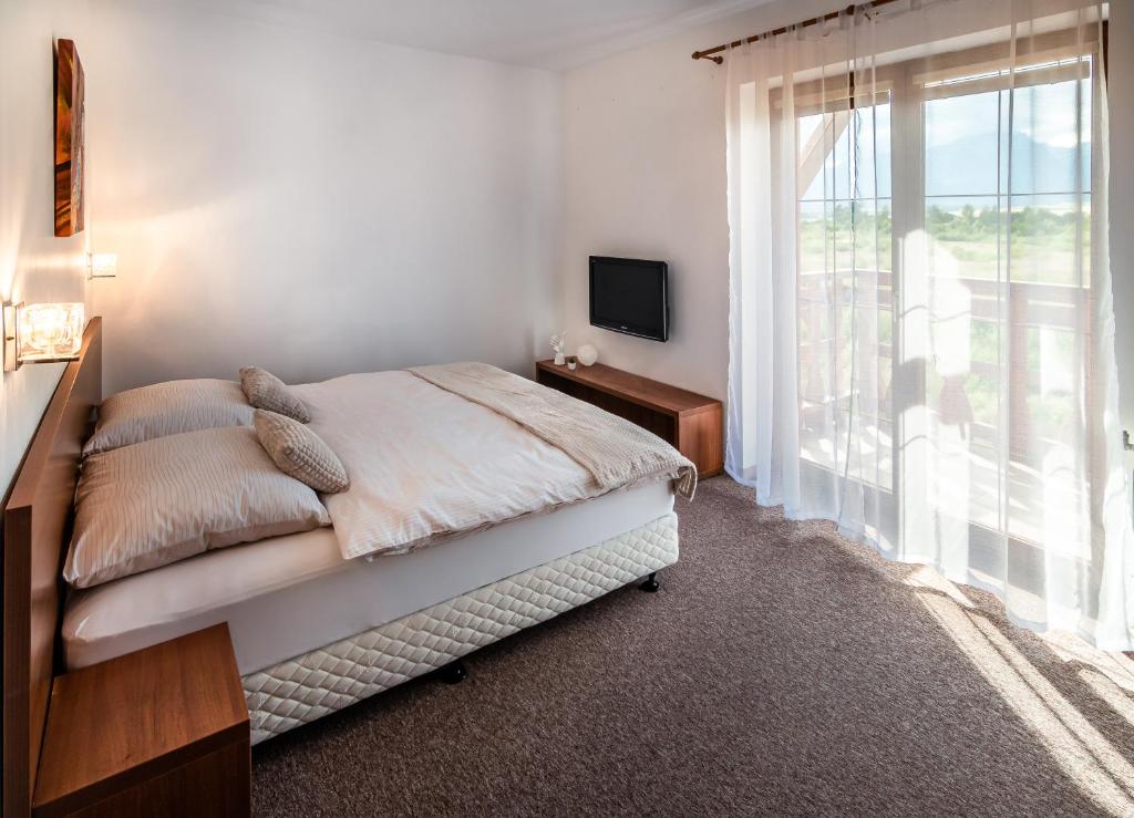 a bedroom with a bed and a large window at apartmán Ela - TATRY GOLF in Veľká Lomnica