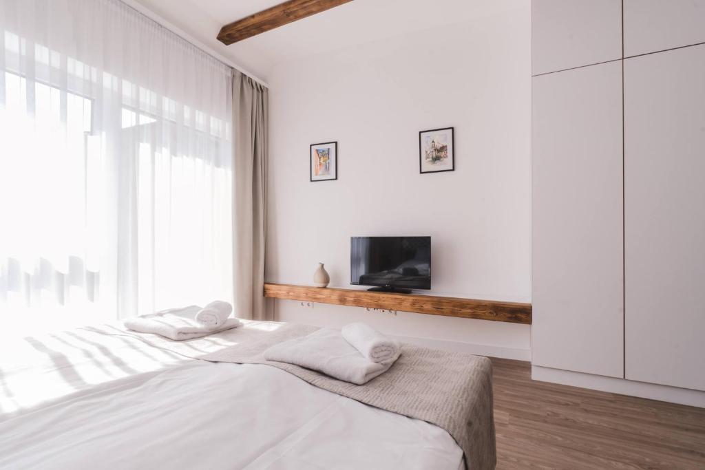 a white bedroom with a bed and a tv at Mathias Rex in Szentendre