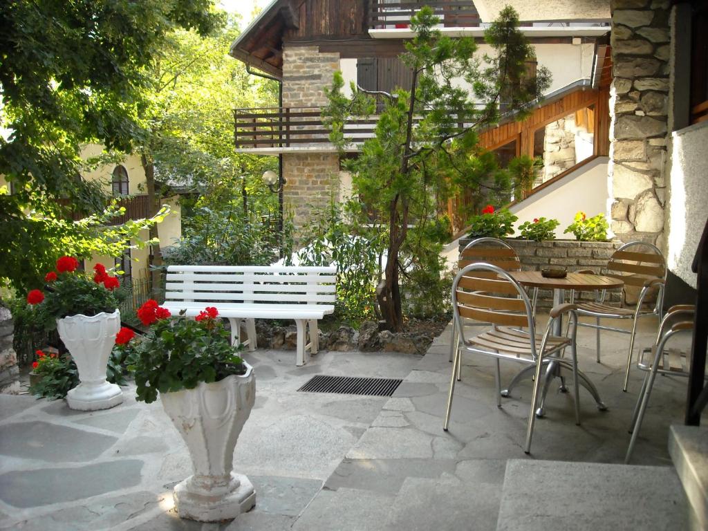 a patio with a white bench and a table and chairs at Hotel Tripoli La Margherita in Limone Piemonte
