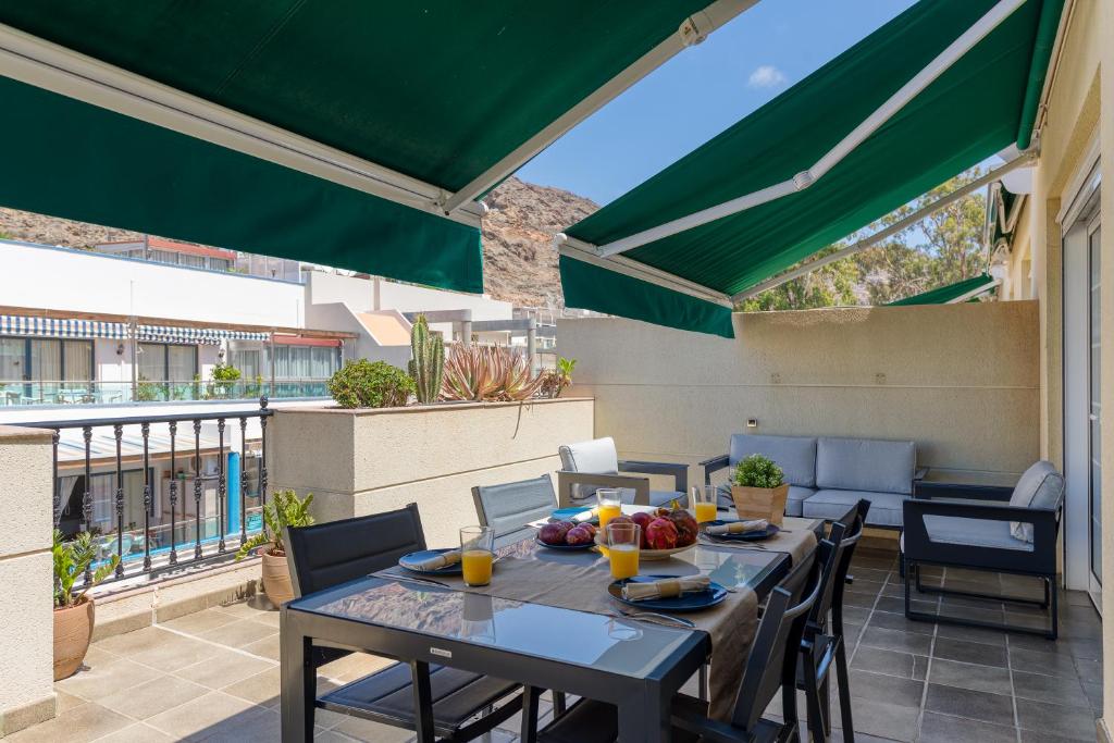 a patio with a table and chairs and a green umbrella at Amarre Moon in Puerto de Mogán