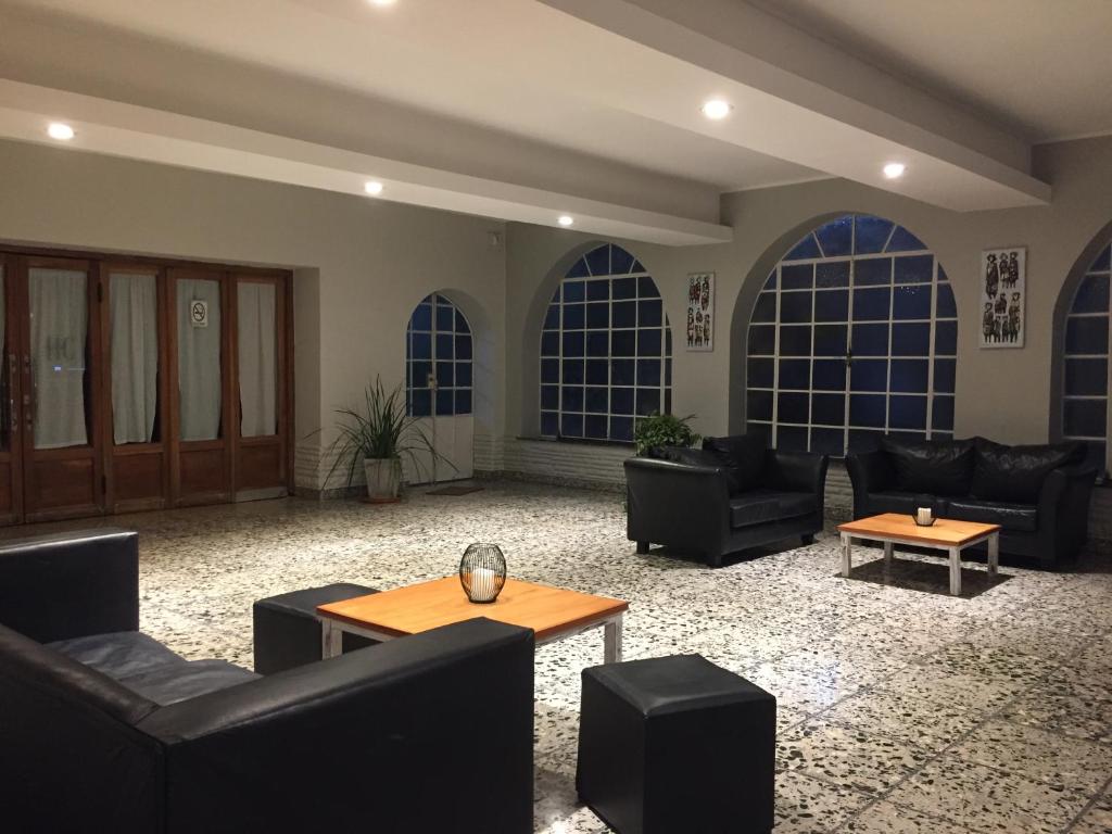 una sala de estar con sofás, mesas y ventanas grandes. en Continental Hotel en Curuzú Cuatiá