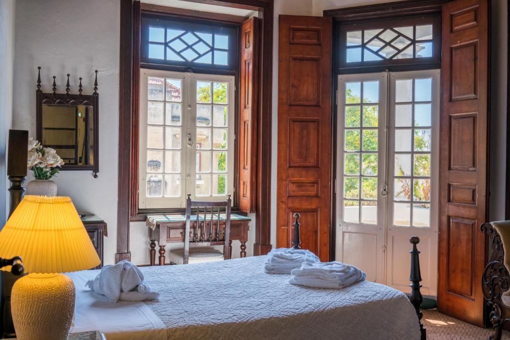 a bedroom with a bed with a lamp and windows at Hotel Residencial Alentejana in Coimbra