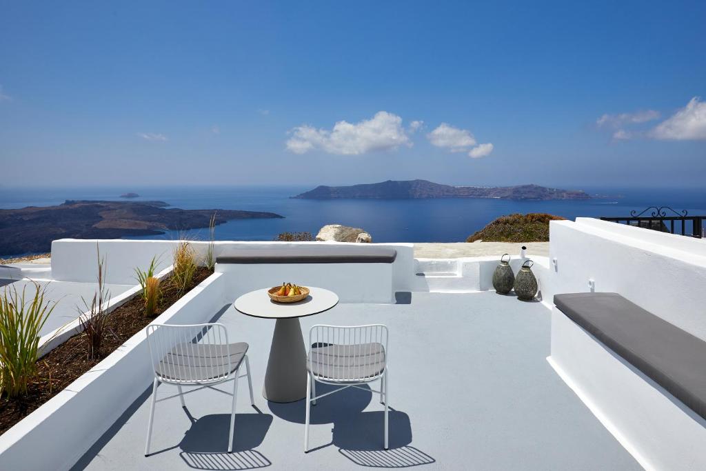 a white patio with a table and chairs on a balcony at Divine View Sol Homes in Fira