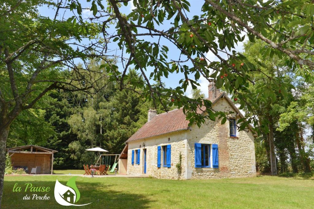 mały kamienny dom z niebieskimi okiennicami na dziedzińcu w obiekcie La Pause du Perche - gîte au pied de la forêt w mieście La Perrière