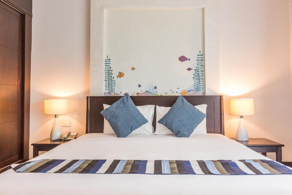 a bedroom with a large bed with blue pillows at Krabi Aquamarine Resort - SHA Plus in Ao Nang Beach
