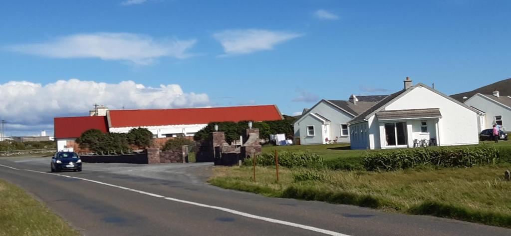 a car driving down a road next to a house at Creevagh (Room Only) in Keel