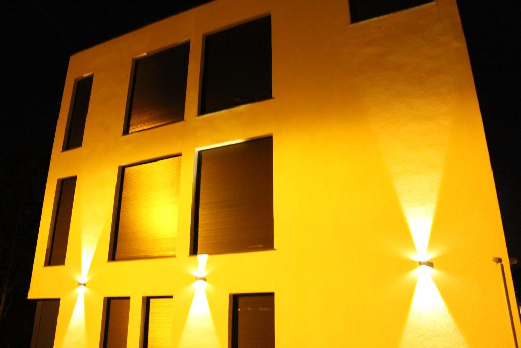 ein gelbes Gebäude mit seitlicher Beleuchtung in der Unterkunft Lovely Studio Cologne West - Neues Momomotel in Köln