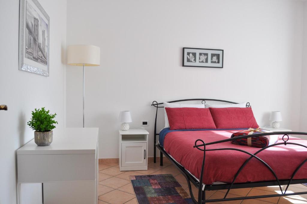 Un dormitorio con una cama con almohadas rojas y una mesa. en B&B Sarita's Rooms, en Certosa di Pavia