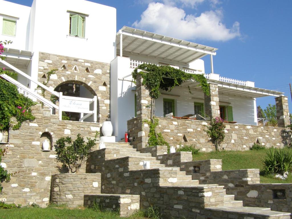 Casa blanca con pared de piedra y escaleras en Elena Studios & Apartments, en Piso Livadi