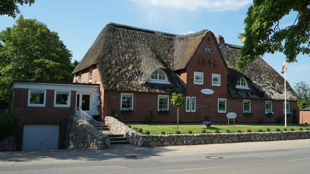 a large red brick building with a thatched roof at Landhaus Gonnsen in Emmelsbüll-Horsbüll