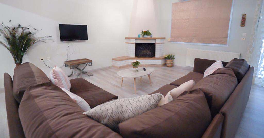 a living room with a brown couch and a fireplace at ThirtyFive Apartment in Aridaia