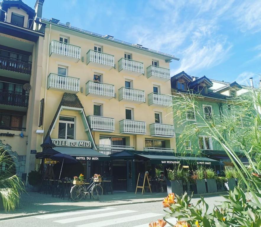 un grand bâtiment jaune avec des balcons blancs. dans l'établissement Hôtel Du Midi, à Thônes