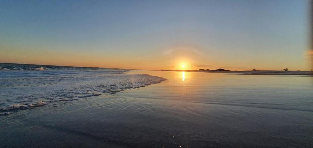 a sunset on the beach with the sun setting at Apart-Hotel Golden Lake 2 in Arraial do Cabo