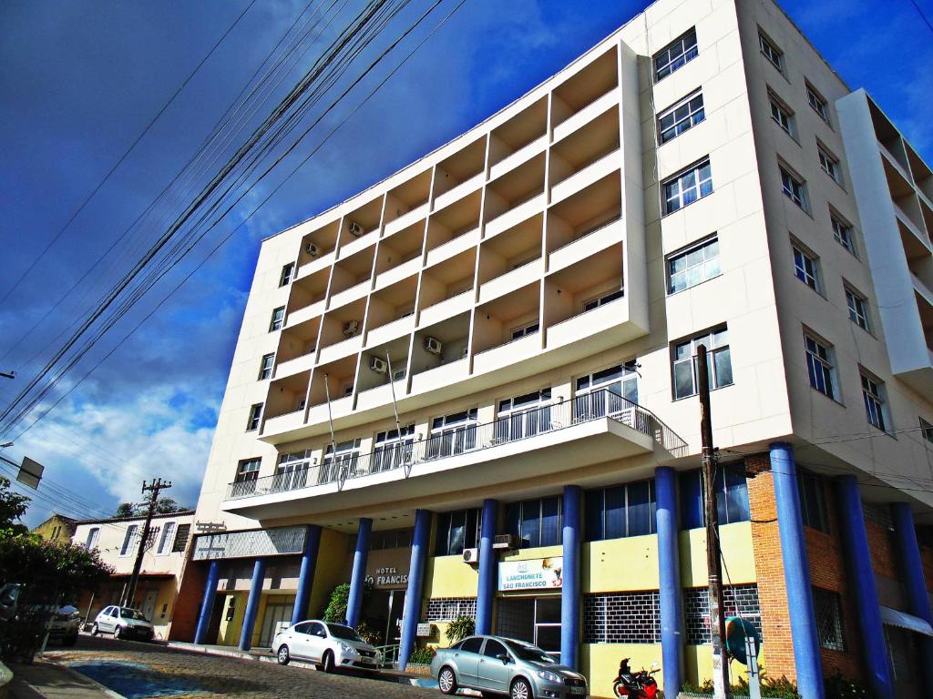 um edifício branco com carros estacionados em frente em Hotel São Francisco em Penedo