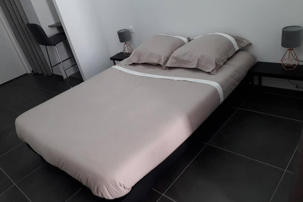 Elle comprend un grand lit avec des draps et des oreillers blancs. dans l'établissement Logement neuf de 40 m², équipé et confortable, à Croix-Chapeau