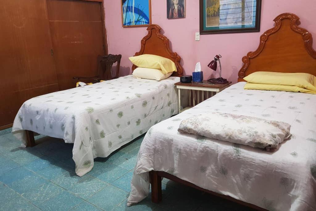 a bedroom with two beds with white sheets and a table at Acogedora habitación en excelente ubicación in Mazatlán