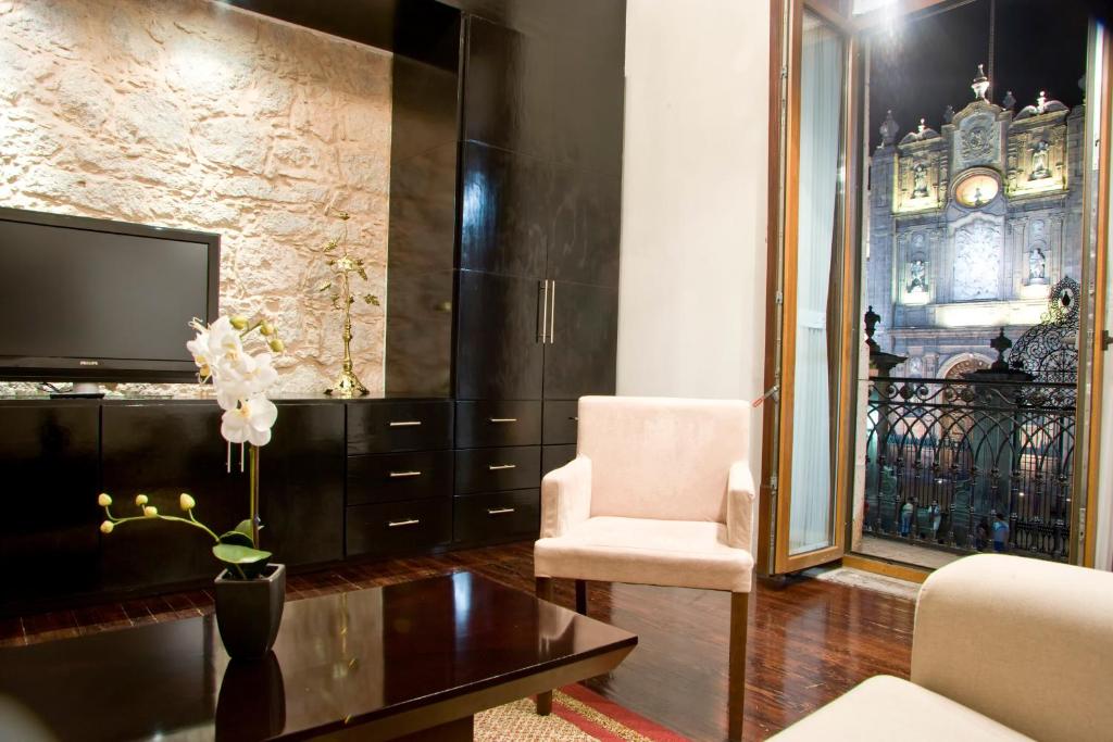 a living room with a tv and a chair at Cantera 10 Hotel Boutique in Morelia
