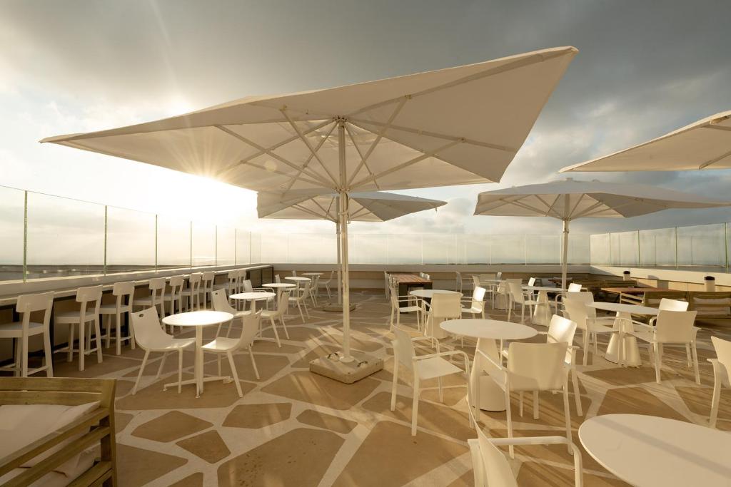 a restaurant with tables and white chairs and umbrellas at Elma Hotel and Art Complex in Zikhron Ya'akov