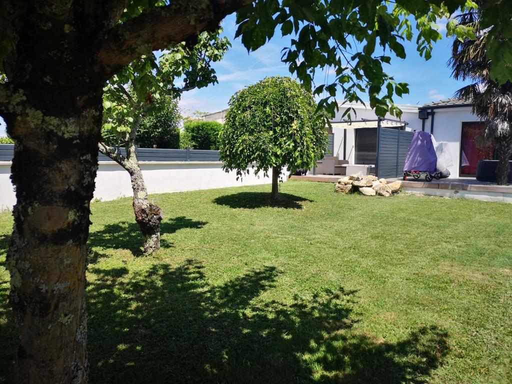 trawnik z dwoma drzewami na podwórku w obiekcie Maison du Moulin w mieście Yvrac