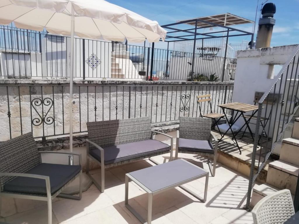 een patio met stoelen en tafels en een parasol bij Le Terrazze Ferrigni in Ostuni