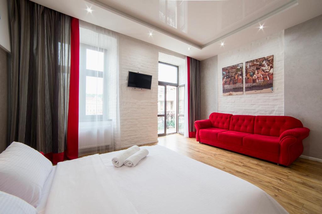 リヴィウにあるMiskevycha Square 5a Apartment- view of the center of Lviv with a balconyの赤いソファと赤いベッドが備わるベッドルーム1室が備わります。