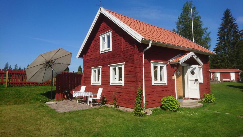 una pequeña casa roja con una mesa y una sombrilla en Barkeryd Norrtorpet en Nässjö