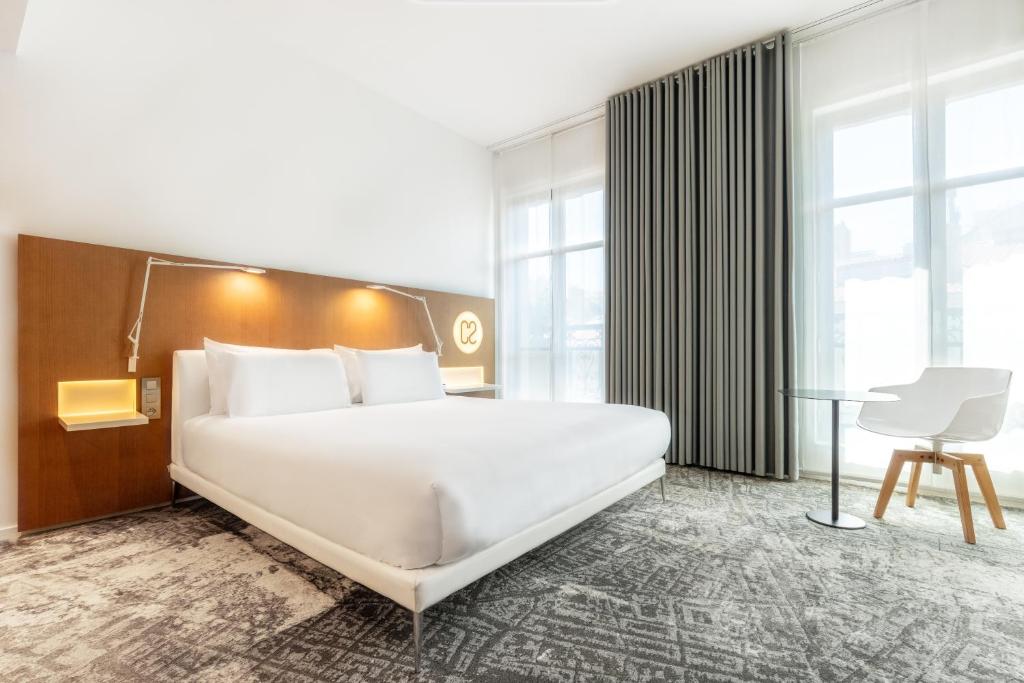 a bedroom with a large white bed and a desk at Hotel C2 in Marseille