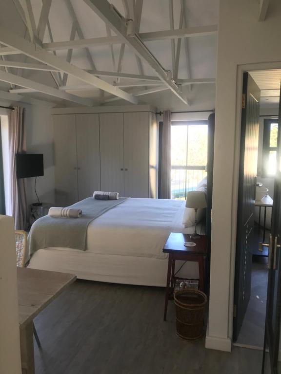 Un dormitorio con una gran cama blanca y una mesa en Comfortable Room with Large en suite Bathroom, en Franschhoek