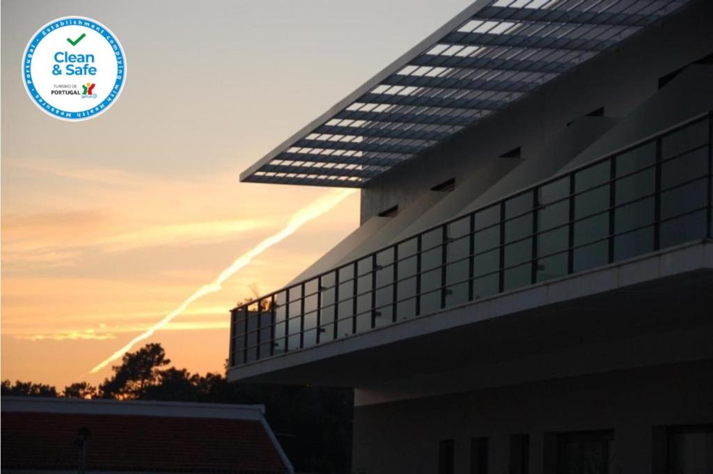 a building with the sun setting in the background at Alojamento Local Verde e Mar in Comporta