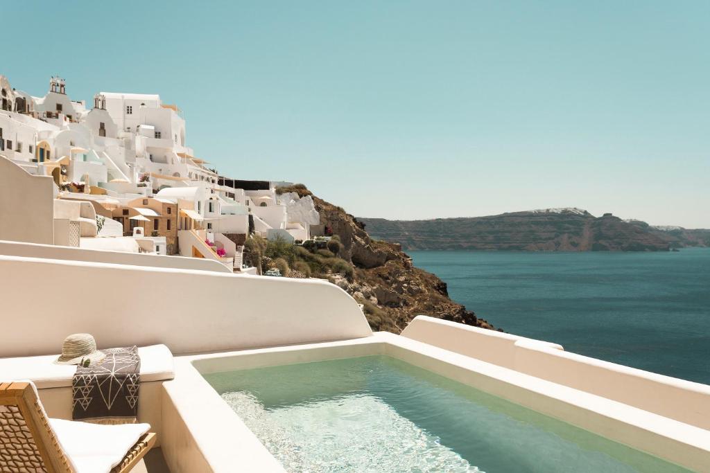a swimming pool with a view of the ocean and buildings at Armenaki in Oia