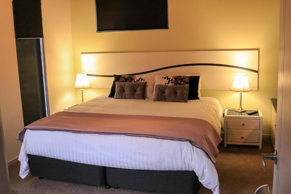 a bedroom with a large bed with two lamps at Ulverstone River Retreat in Ulverstone