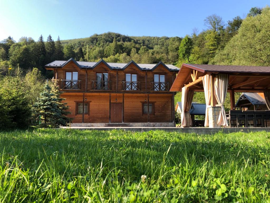 a large wooden house with a gazebo in a field at Брусний View House in Sheshory