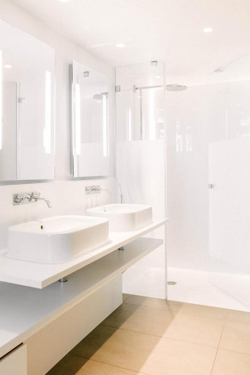 a white bathroom with two sinks and a shower at Hotel C2 in Marseille