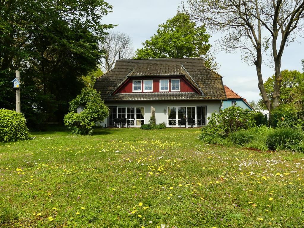 a house with a red roof on a green field at Ferienwohnungen Jagdhaus 6 in Wieck