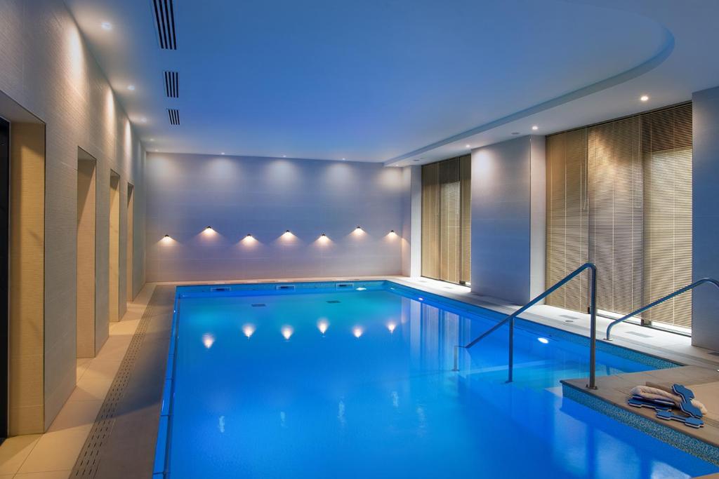 a swimming pool in a building with a blue lighting at Domitys - Galilée in Cergy