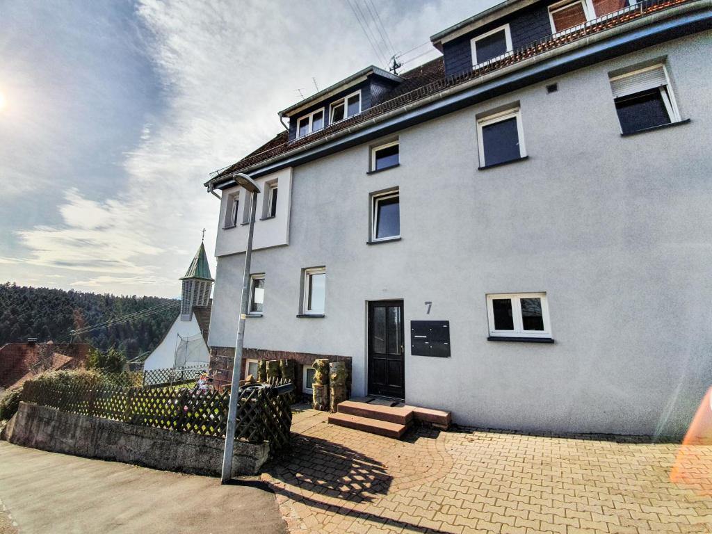 un gran edificio blanco con una iglesia al fondo en Ferienwohnung Schwarzwaldblick, en Unterreichenbach