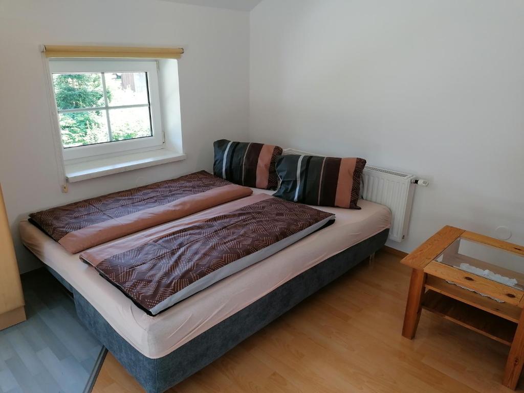 Bett in einem Zimmer mit einem Fenster und einem Tisch in der Unterkunft Haus Tressenstein in Bad Aussee