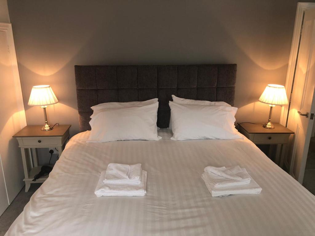 a bedroom with two towels on a bed with two lamps at Queen Street Apartments in Enniskillen