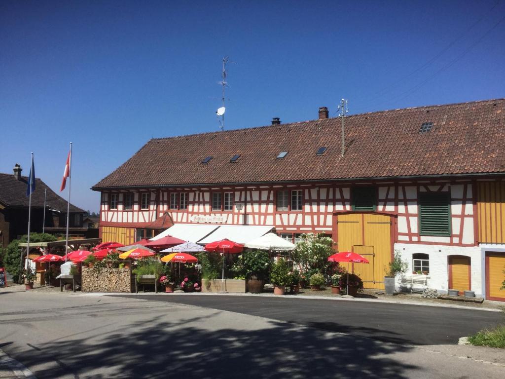 un bâtiment avec des parapluies rouges et blancs devant lui dans l'établissement Gasthaus Freihof, 