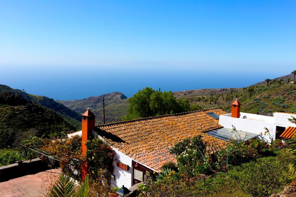 a white house with a roof with mountains in the background at El Drago Rural House in Alajeró