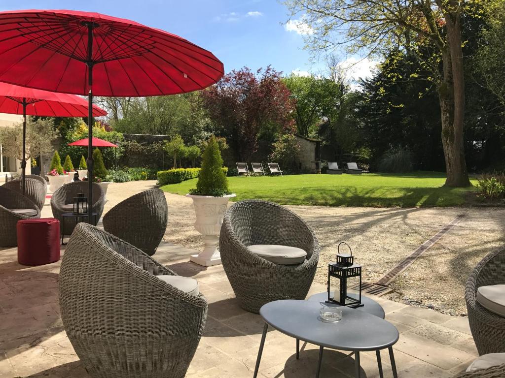 a group of chairs and tables with a red umbrella at Le Tardif, Noble Guesthouse in Bayeux