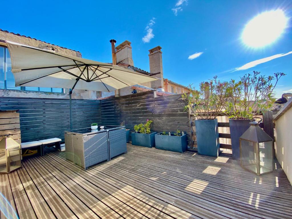 une terrasse avec un parasol et des plantes en pots dans l'établissement Èrsextius, LGLL1, Aix-en-Provence, à Aix-en-Provence